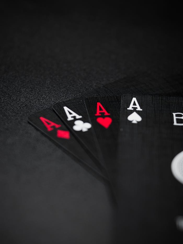 Close-up view of four black playing aces on a dark background, symbolizing luck and gambling.