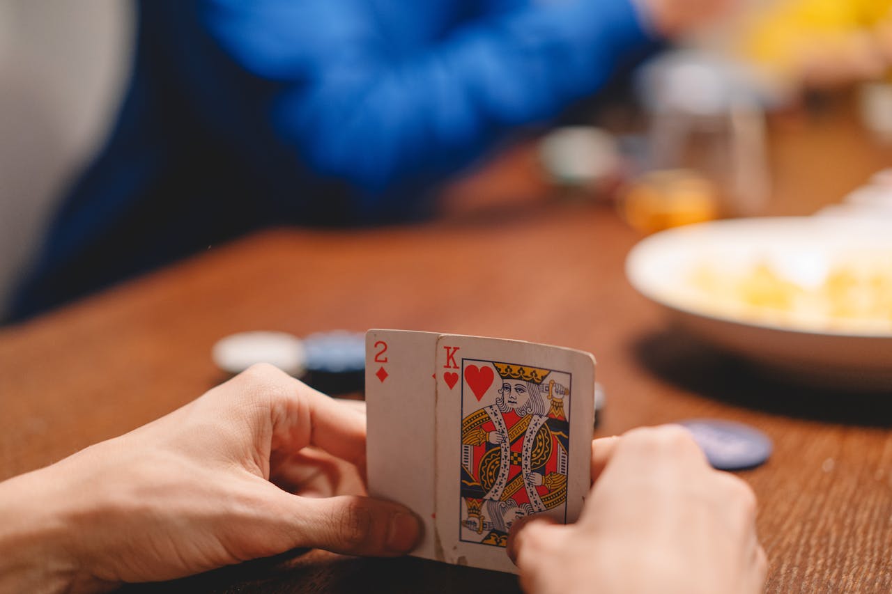 Close-up of a person holding playing cards during a poker game, focused on strategy and excitement.
